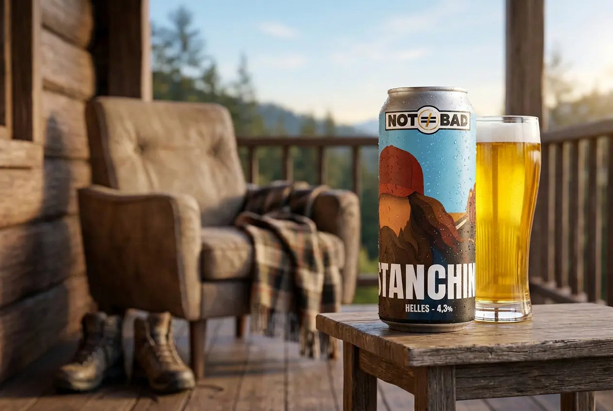 Stanchino Helles beer can and glass on a wooden table in a rustic setting.